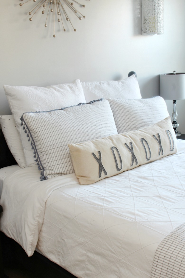 Black farmhouse style bed frame with white bedding and blue accents.
