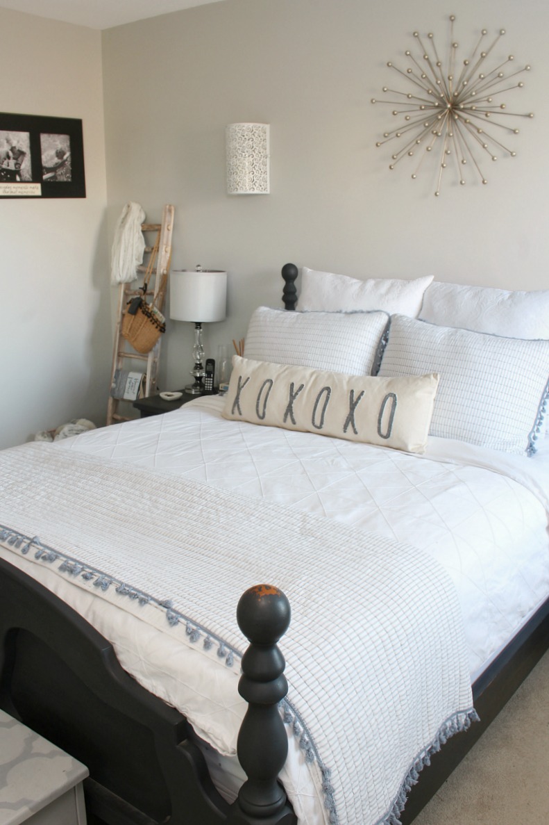 Black farmhouse style bed frame with white bedding and blue accents.